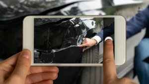 Person taking a photo of car damage with a smartphone after an accident.