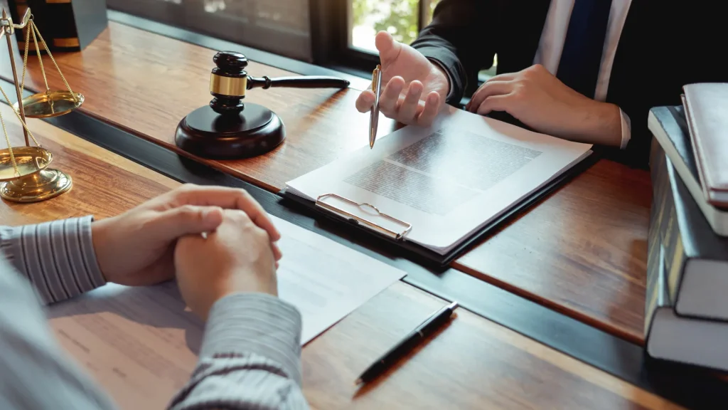 Legal discussion with documents, a gavel, and hands gesturing.